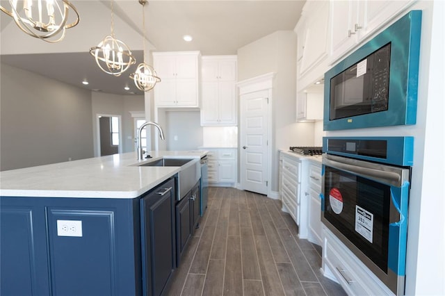 kitchen with dark wood-style floors, a notable chandelier, white cabinets, black microwave, and oven