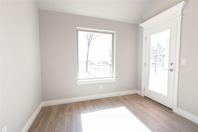 doorway featuring plenty of natural light, baseboards, and light wood-style flooring