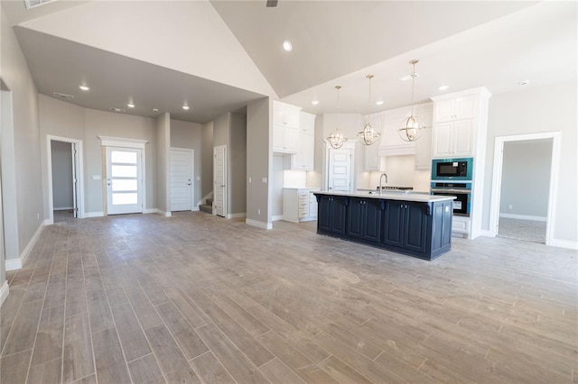 kitchen featuring black microwave, a sink, stainless steel oven, white cabinetry, and light countertops