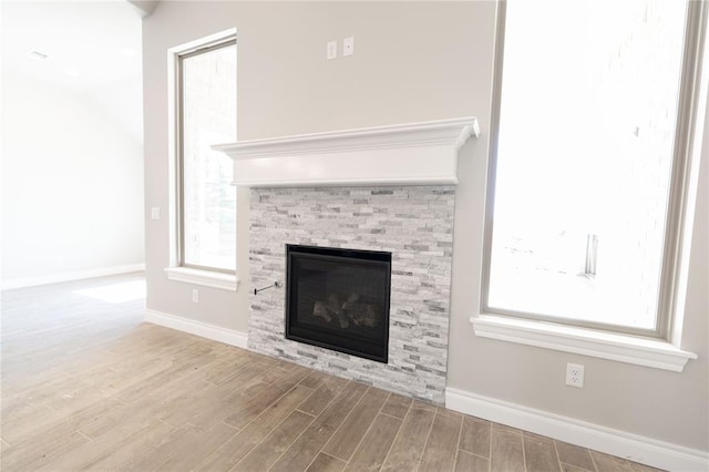 details featuring wood finished floors, a glass covered fireplace, and baseboards