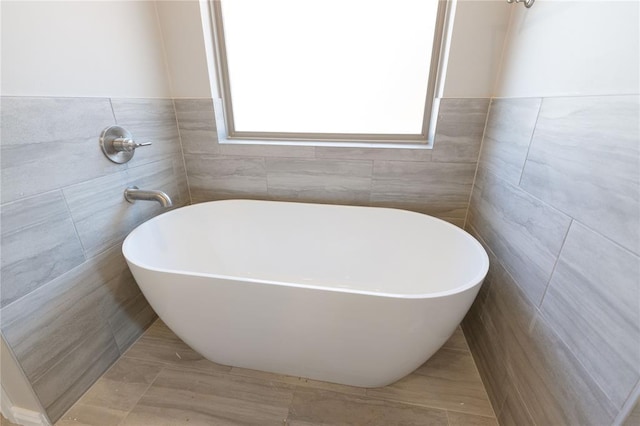 full bathroom featuring a freestanding bath and tile walls