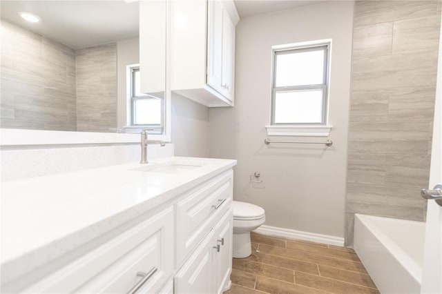 full bath featuring wood finish floors, baseboards, vanity, and toilet