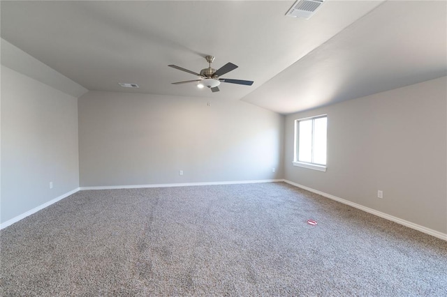 carpeted spare room featuring lofted ceiling, visible vents, and baseboards