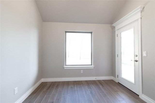 empty room with baseboards, lofted ceiling, and dark wood-style floors