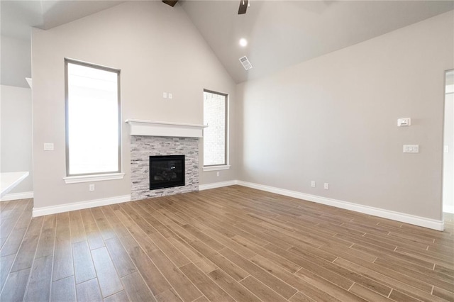 unfurnished living room featuring wood finished floors, visible vents, a ceiling fan, baseboards, and high vaulted ceiling