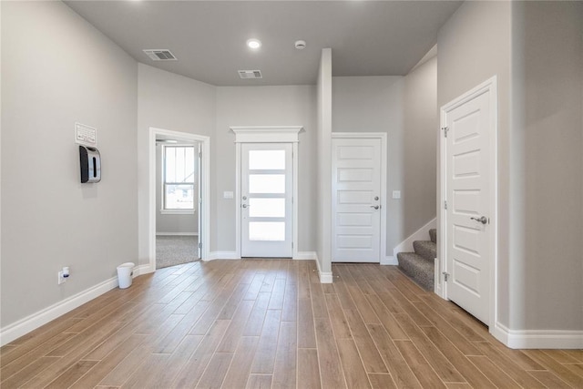 foyer entrance featuring stairs, light wood-style floors, and visible vents