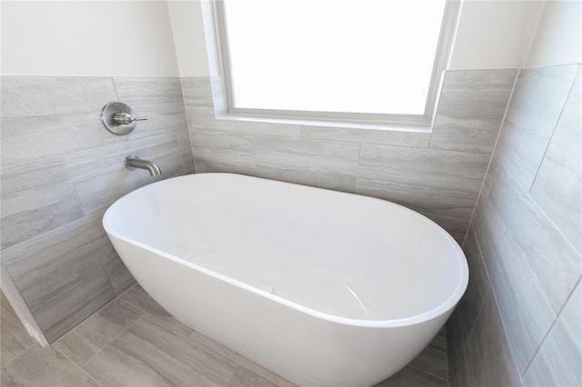 full bath with plenty of natural light, a soaking tub, and tile walls