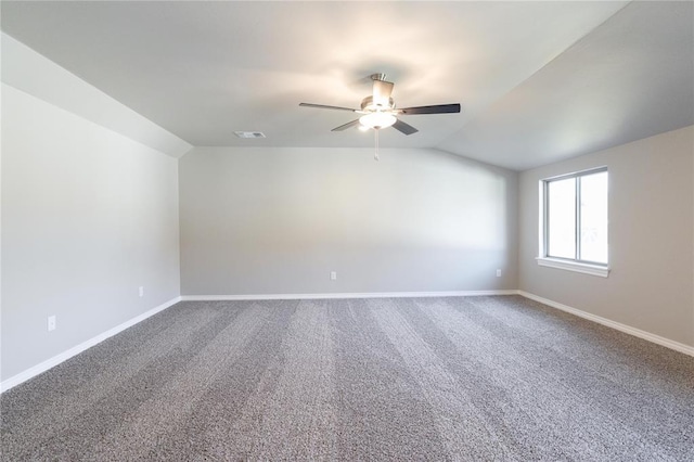 carpeted empty room with ceiling fan, vaulted ceiling, visible vents, and baseboards
