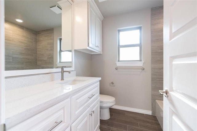 full bathroom with toilet, a washtub, baseboards, vanity, and wood finish floors