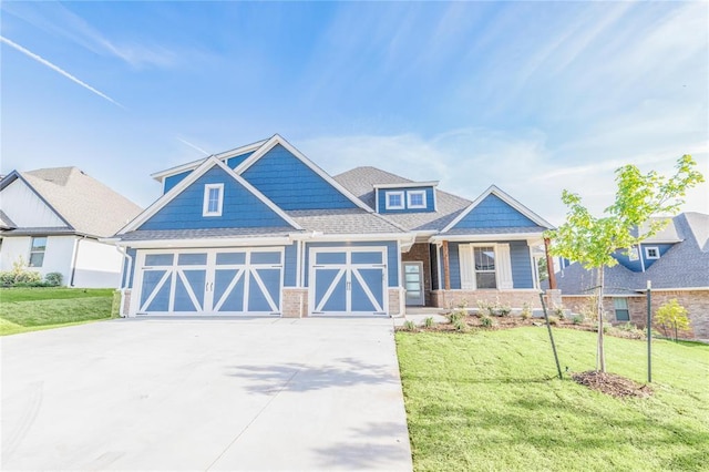 craftsman inspired home with a garage, driveway, a front lawn, and brick siding