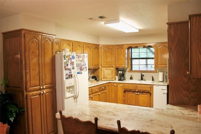 kitchen with a textured ceiling, kitchen peninsula, sink, and white appliances