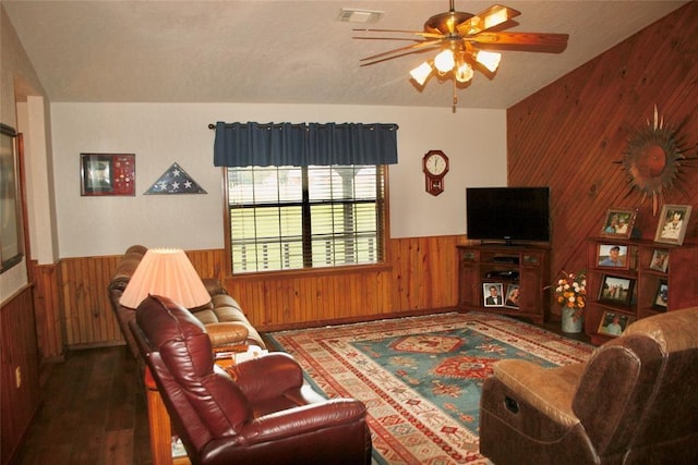 living room with ceiling fan, dark hardwood / wood-style flooring, lofted ceiling, and wooden walls