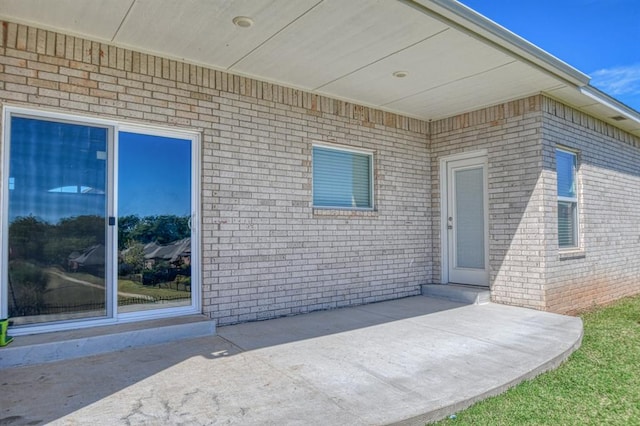 view of exterior entry with a patio area