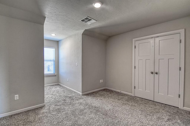 carpeted spare room featuring a textured ceiling