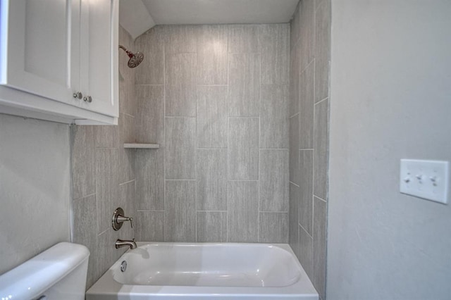 bathroom featuring tiled shower / bath combo and toilet