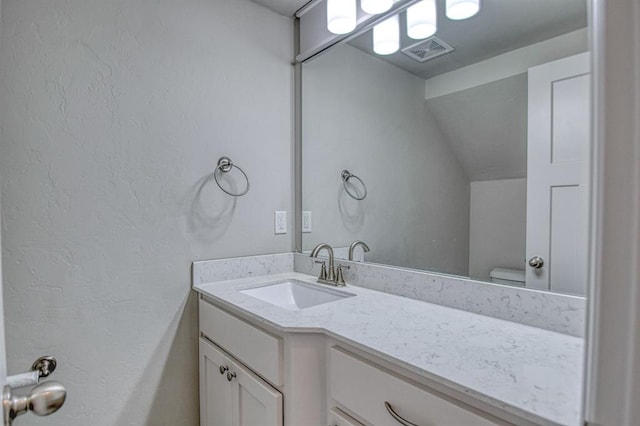 bathroom with vanity, toilet, and vaulted ceiling