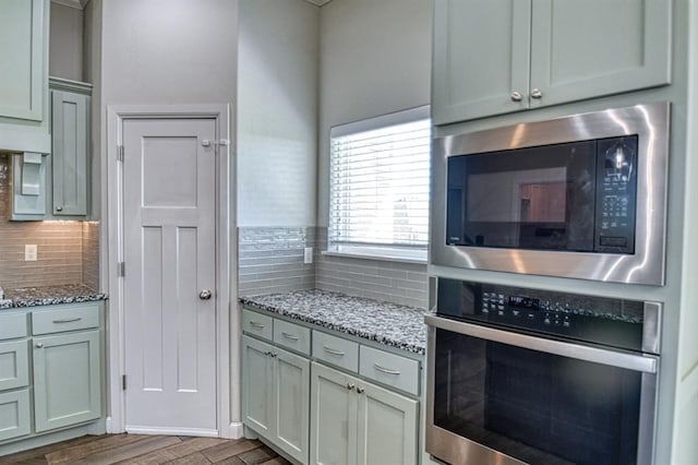 kitchen featuring light stone counters, wood-type flooring, backsplash, and appliances with stainless steel finishes