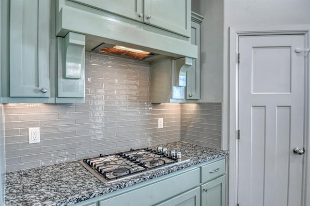 kitchen featuring stainless steel gas stovetop, dark stone countertops, and tasteful backsplash