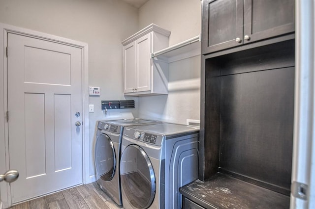 clothes washing area with cabinets, dark hardwood / wood-style flooring, and washer and clothes dryer