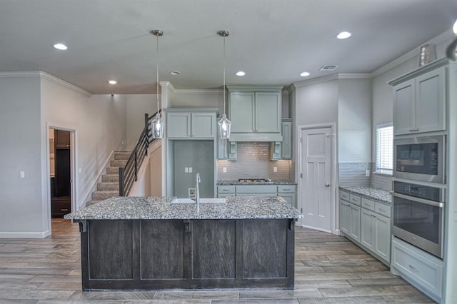 kitchen featuring light stone counters, an island with sink, and stainless steel appliances