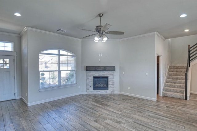 unfurnished living room featuring ceiling fan, light hardwood / wood-style floors, ornamental molding, and a fireplace