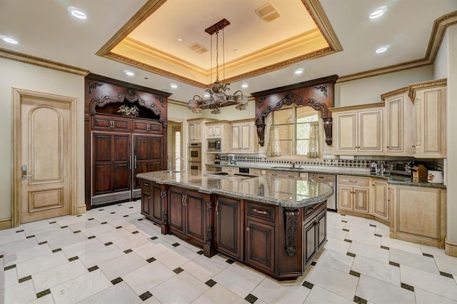 kitchen with decorative light fixtures, a raised ceiling, a kitchen island with sink, and tasteful backsplash