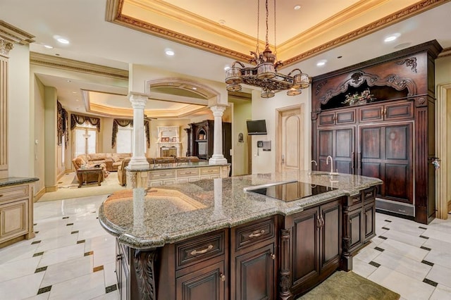 kitchen with a spacious island, ornamental molding, hanging light fixtures, and decorative columns