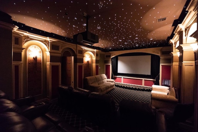 cinema featuring a towering ceiling, carpet floors, ornate columns, and crown molding