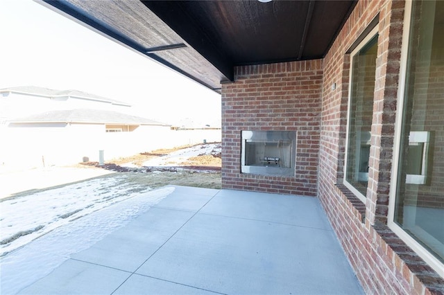 snow covered patio with an outdoor brick fireplace