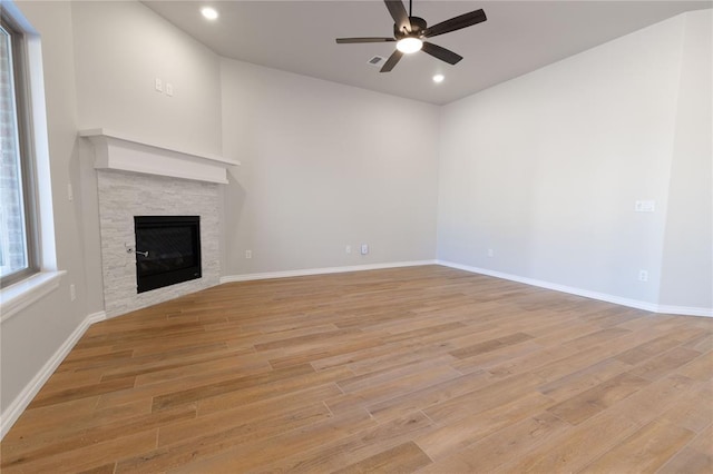 unfurnished living room featuring a tile fireplace, ceiling fan, and light hardwood / wood-style floors