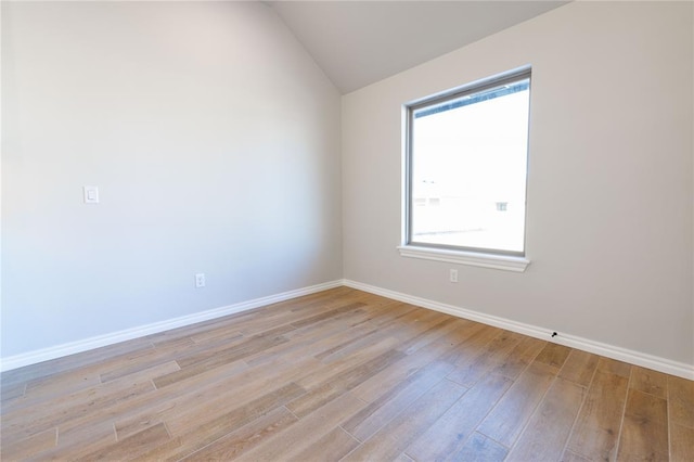 spare room featuring a wealth of natural light, light hardwood / wood-style flooring, and vaulted ceiling