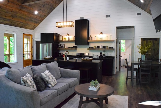 living room featuring sink, high vaulted ceiling, an inviting chandelier, dark hardwood / wood-style floors, and wood walls