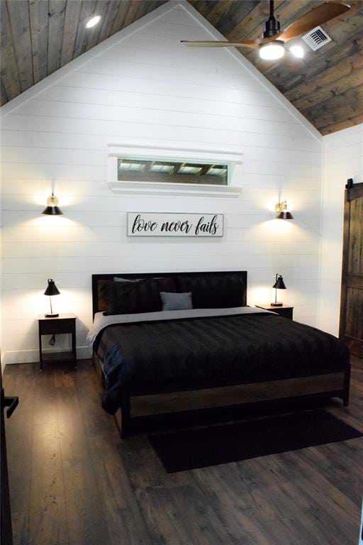 bedroom with a barn door, high vaulted ceiling, ceiling fan, and dark wood-type flooring