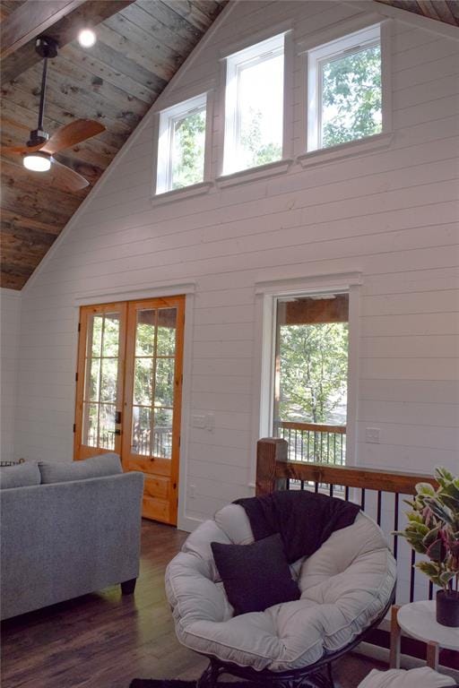 living room featuring ceiling fan, french doors, dark wood-type flooring, high vaulted ceiling, and wood walls