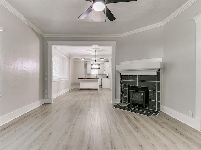 unfurnished living room featuring hardwood / wood-style floors, ceiling fan, a wood stove, and crown molding