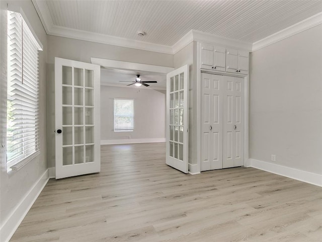 empty room with crown molding, french doors, and light hardwood / wood-style flooring