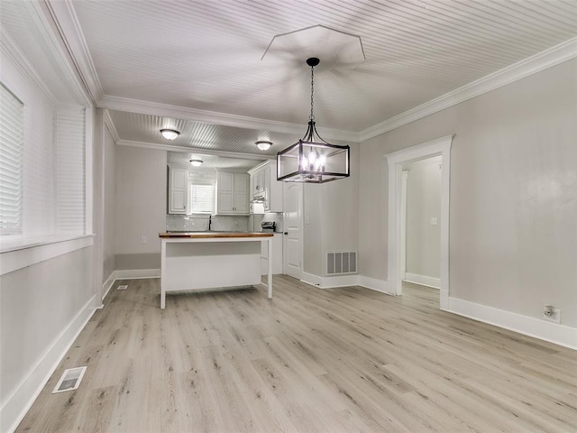 interior space with wood counters, light hardwood / wood-style floors, ornamental molding, and hanging light fixtures