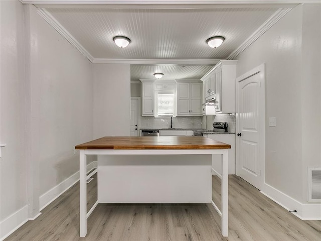 kitchen with a breakfast bar area, ornamental molding, wooden counters, and stainless steel appliances