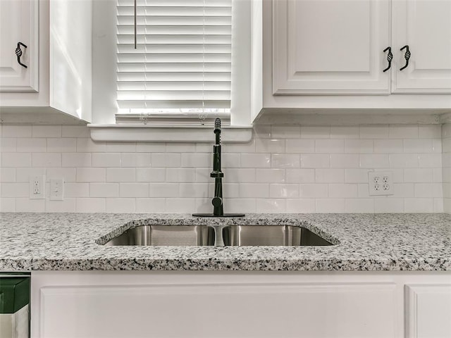 kitchen featuring decorative backsplash, light stone counters, white cabinetry, and sink