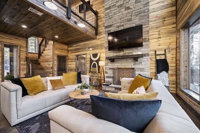 living room featuring wood walls, a healthy amount of sunlight, and a high ceiling