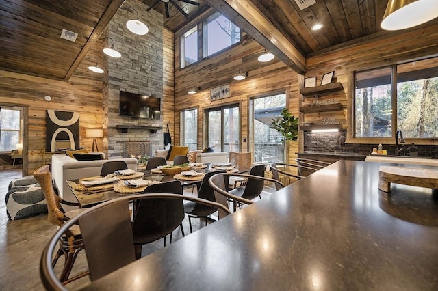 dining space with beam ceiling, a fireplace, plenty of natural light, and high vaulted ceiling