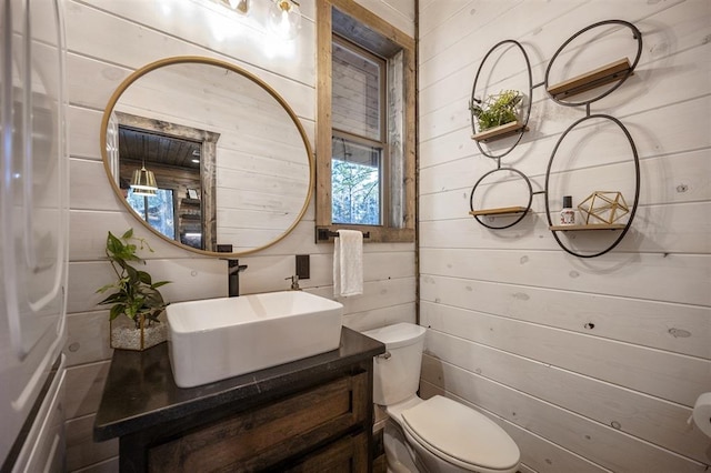 bathroom with wood walls, vanity, and toilet