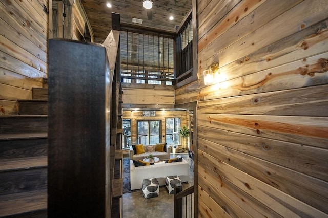 interior space with wood ceiling, a high ceiling, and wooden walls