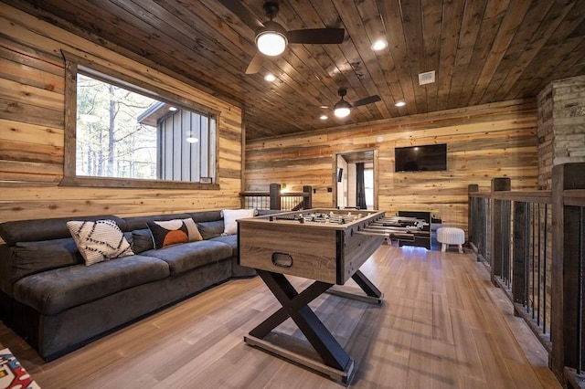 recreation room with ceiling fan, light hardwood / wood-style floors, wood ceiling, and wooden walls