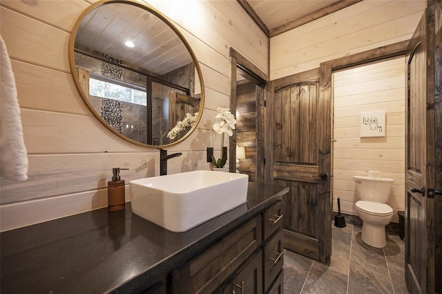 bathroom with vanity, wood walls, toilet, and wooden ceiling