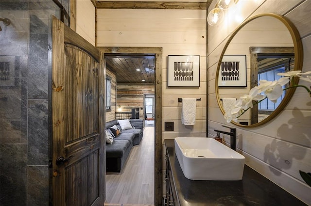 bathroom featuring hardwood / wood-style floors, vanity, and wooden walls