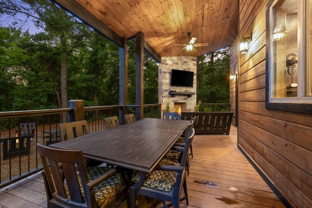 wooden terrace featuring an outdoor stone fireplace and ceiling fan