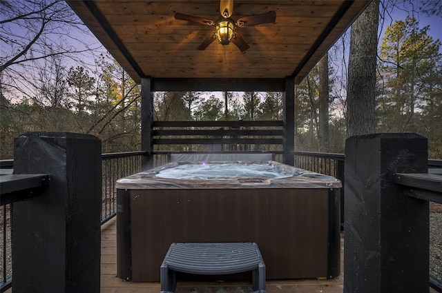 deck at dusk with ceiling fan and a hot tub