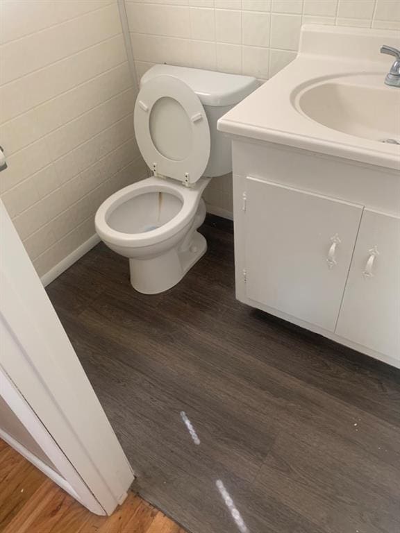 bathroom featuring hardwood / wood-style floors, vanity, toilet, and tile walls