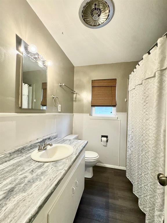 bathroom featuring toilet, hardwood / wood-style floors, vanity, and vaulted ceiling